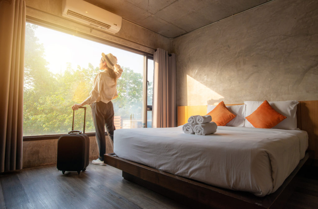 Tourist woman with her luggage in hotel bedroom.