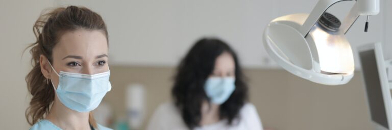 Young female nurse working with assistant while treating patient in modern hospital