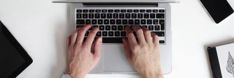 male typing on macbook