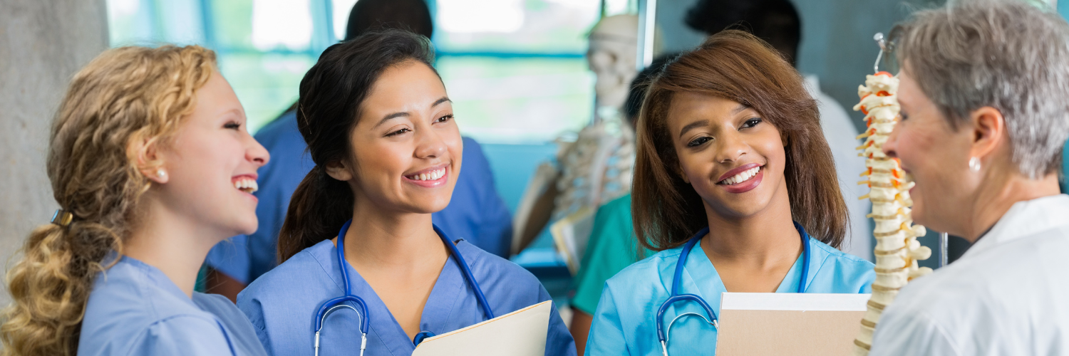 Female nursing or medical students studying spine model in class